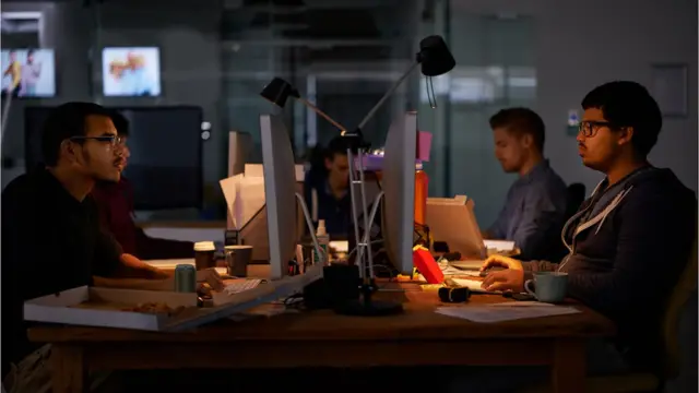 Hombres trabajando en computadoras (crédito: iStock)