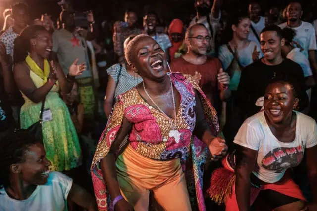 People dance and sing next to Ugandan singer Jackie Akello (C) during the 16th International African music festival 'Sauti za Busara' at the Old Fort in Stone town, Zanzibar, on 8 February 2019.