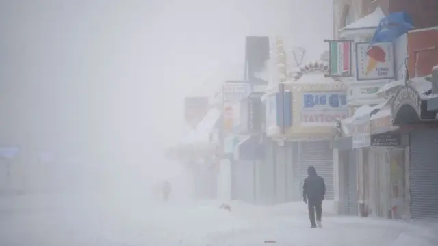 pria berjalan di tengah badai salju