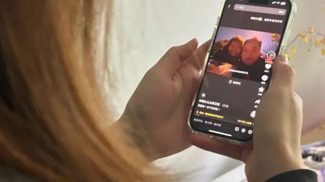 Genç bir kadın akıllı telefonundan Pan ve Zhang'ın hesaplarına bakıyor.