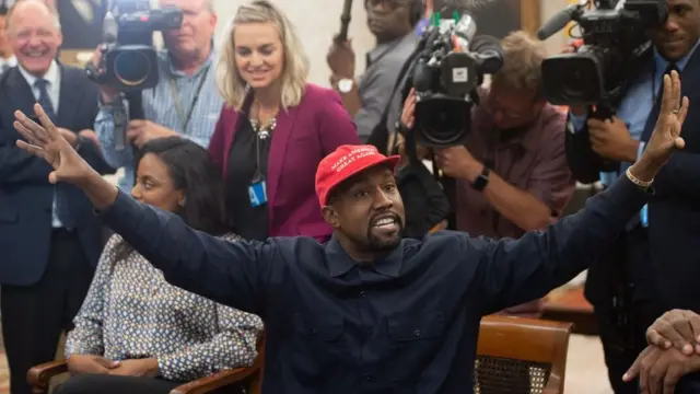 Kanye West con una gorra de Make America Great Again y rodeado de periodistas.
