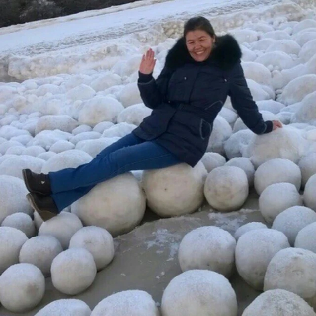 A picture showing a smiling woman lying across the snowballs in the Yamal Peninsula