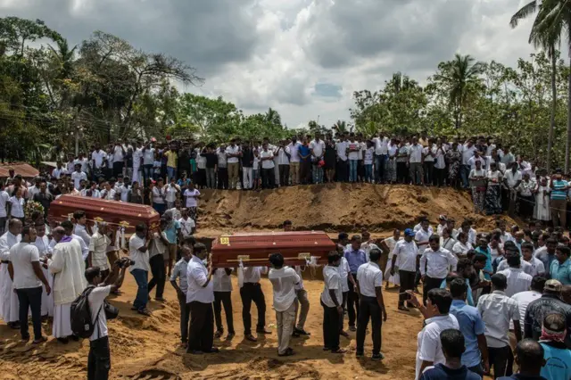 Coffins are carried to a grave during a mass funeral at St Sebastian's Church on 23 April in Negombo, Sri Lanka. A wave of bombings targeting churches and hotels left more than 250 people dead and many more injured.