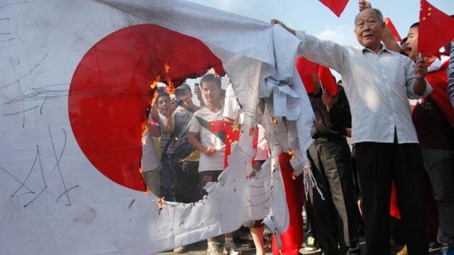 日本の国旗を焼くデモ参加者