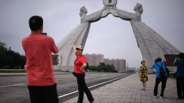 Tourists post in front of a statue of two women in Pyongyang (file image)