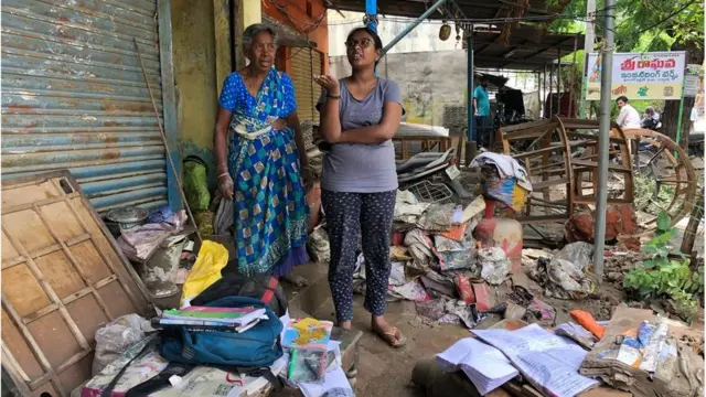 తడిచిపోయిన వస్తువులను చూపిస్తున్న బాధితులు