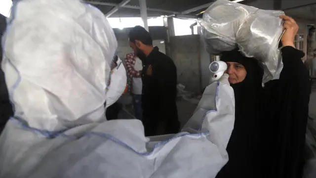 A health worker checks the temperature of an Iraqi woman upon her arrival at the Shalamcheh border crossing with Iran (20 February 2020)
