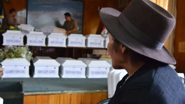 Una mujer frente a unos ataúdes de personas muertas durante el conflicto interno en Perú.