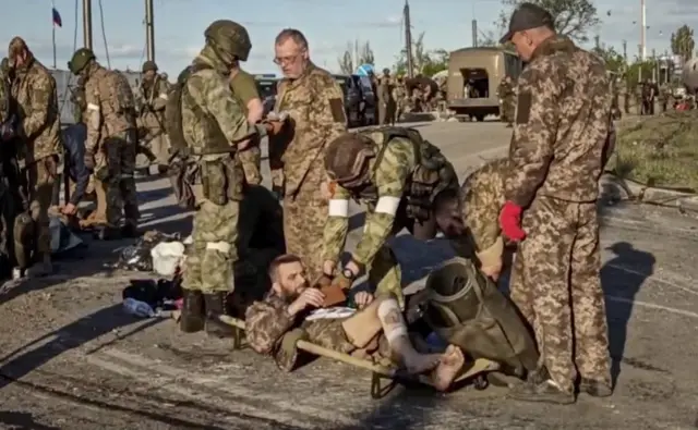 A handout still image taken from a handout video made available by the Russian Defence Ministry"s press service shows Russian servicemen frisk Ukrainian servicemen as they are being evacuated from the besieged Azovstal steel plant in Mariupol, Ukraine, 17 May 2022.