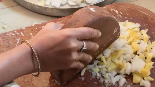 Рука с камнем, дробящая чеснок с имбирем