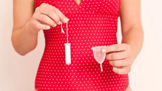 한 여성이 탐폰과 생리컵을 들고 있다