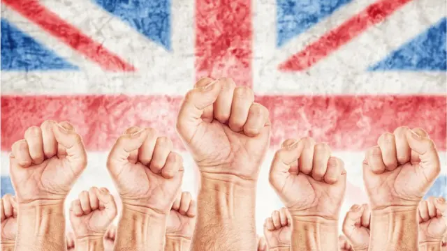 Сжатые в кулак руки на фоне британского флага
