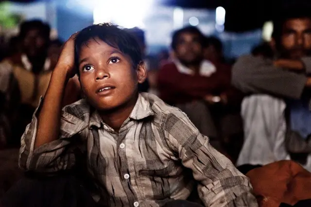 ટ્રાવેલિંગ સિનેમા નિહાળતા બાળકનો ફોટો