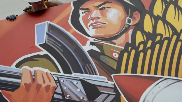 A worker takes down a poster for The Interview, after cinema chains refused to show it