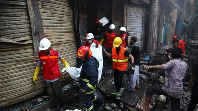 Volunteers recover a dead body from a burnt warehouse in Dhaka