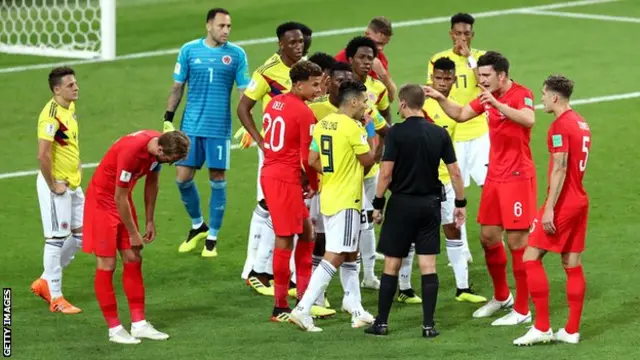 Colombia and England players surround referee Mark Geiger