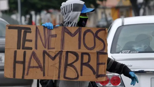 Hombre sostiene un cartel que dice Tenemos Hambre