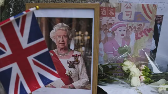 香港英国领事馆外民众摆放英女王伊丽莎白二世遗像与纪念她1975年访问香港的绘画（10/9/2022）