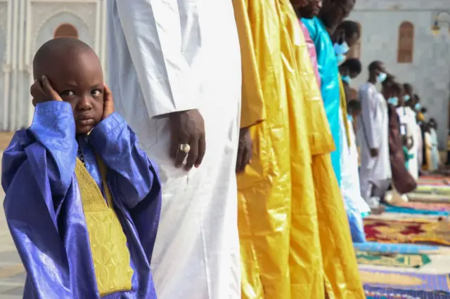 A boy cups his ears during prayers at the mosque.
