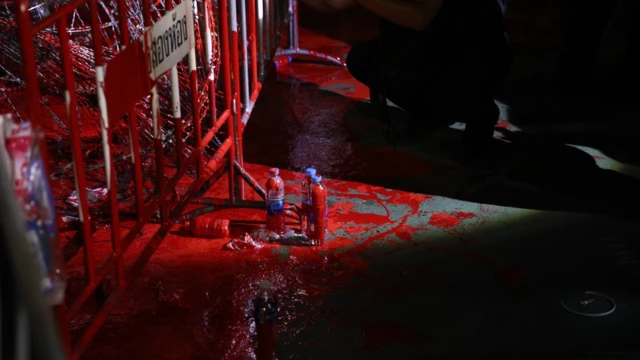 ผู้ชุมนุมได้ทำกิจกรรมเชิงสัญลักษณ์เทสีแดง ลงที่พื้นและลวดหนามหน้าแนวกั้นของตำรวจ