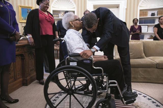Obama kisses a women in a wheelchair