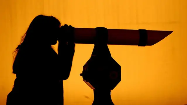 Mujer mirando por un telescopio