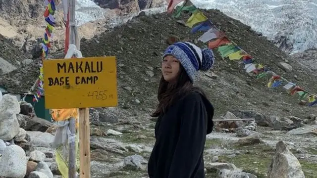 Shiny Dijmarescu standing in front of a sign saying 'Malalu Base Camp, 4755m'