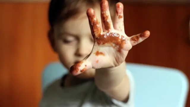 Ребенок с рукой в шоколаде