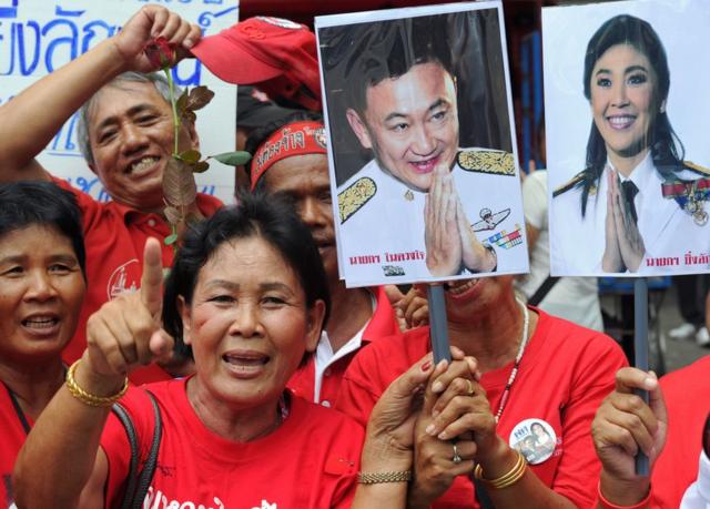 This file photo taken on 5 August 2011 shows "Red Shirt" demonstrators, supporters of fugitive former leader Thaksin Shinawatra (pictured 2nd R), shouting slogans as they gather in support of Thaksin"s sister, the country"s prime minister, Yingluck Shinawatra (pictured R), after she was endorsed into office at parliament in Bangkok.