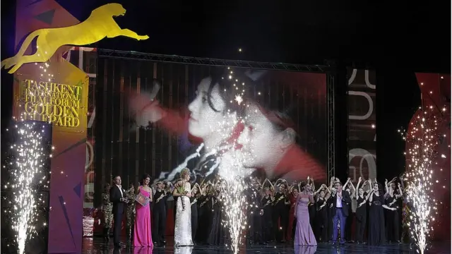 Ceremonia del Guepardo de oro. Grupo de actores participa en coreografía levantando las manos mientras luces y pirotecnia son proyectadas a los lados.