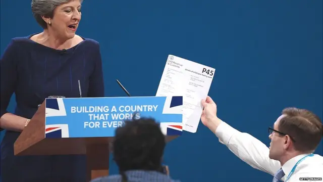 Comedian Simon Brodkin, aka prankster Lee Nelson, hands Prime Minister Theresa May a P45