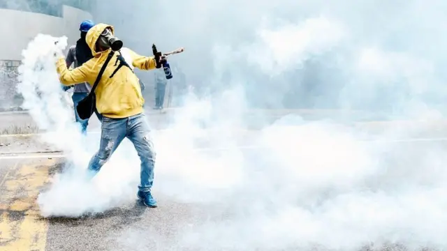 Un opositor venezolano relanza una bomba de gas lacrimógeno durante una protesta contra Nicolás Maduro el 1 de mayo en Caracas.