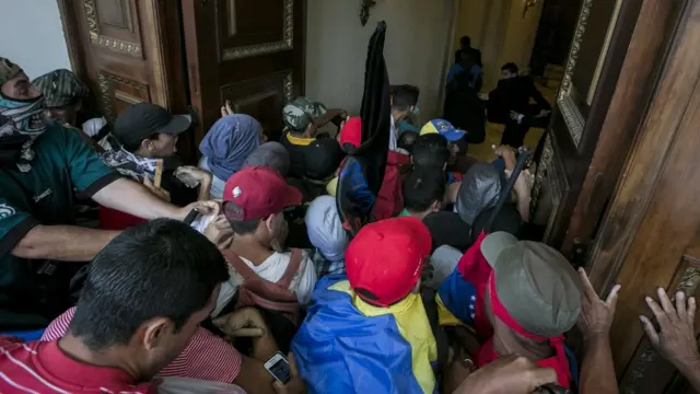 Un grupo de personas empujan una puerta para entrar al Palacio Legislativo.