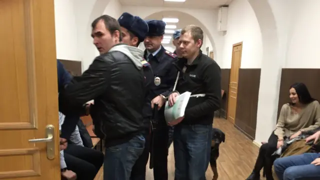 Конвой заводит двоих мужчин в судебный зал