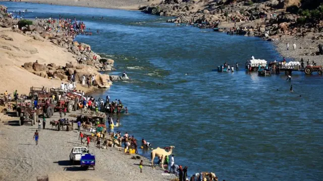 لاجئون يتجمعون على ضفة نهر يقع على الحدود مع السودان بعد أن فروا من القتال في تيغراي.