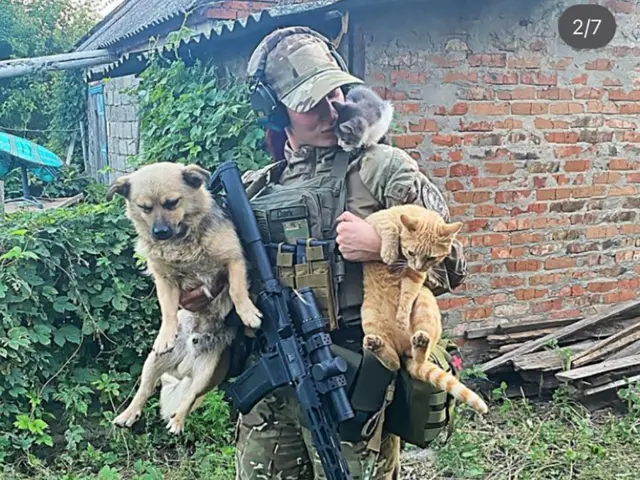 Une image du compte Instagram d'Evgeniya la montre en uniforme tenant un chien et un chat