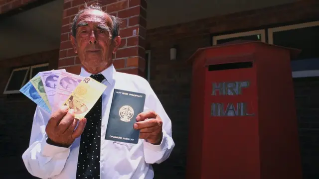 El autoproclamado Príncipe Leonardo muestra el pasaporte y la moneda del principado.