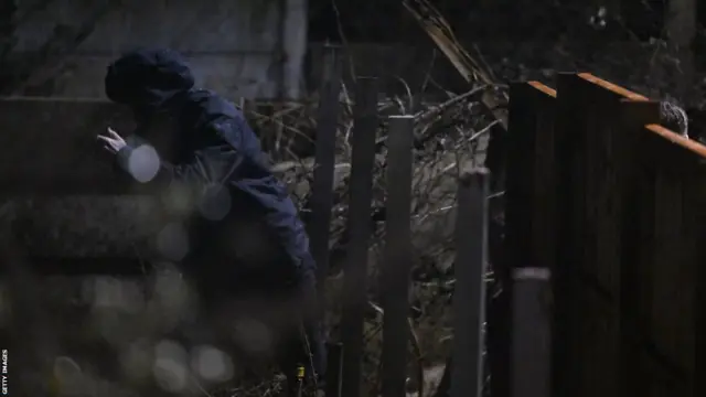 David Beckham climbing over a fencg