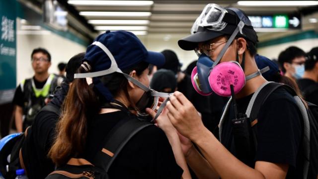 香港九龙港铁尖沙咀站内一名男示威者协助一名女示威者调整防烟口罩（10/8/2019）