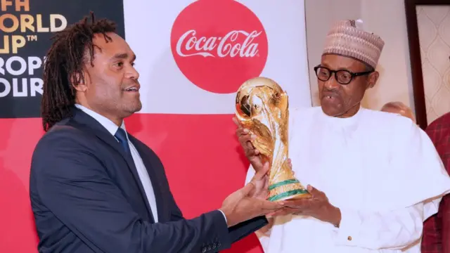 Gbajugbaja agbabọọlu orilẹede France ni, Chritian Karembeu n gbe ife ẹyẹ yii le aarẹ Buhari lọwọ