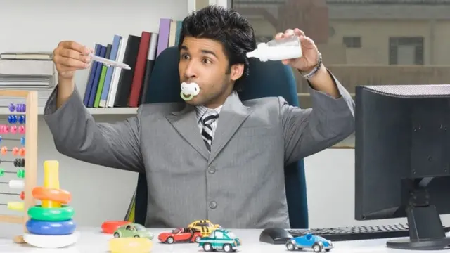 Un adulto jugando con juguetes de bebé en un escritorio