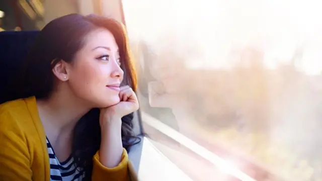 Una mujer mirando por la ventana con expresión de estar soñando despierta