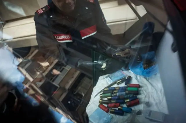 Policial italiano exibe as armas e drogas encontradas em casas no bairro onde viviam integrantes da máfia, no bairro de Ostia, em 1 de dezembro de 2017, em Roma, Itália
