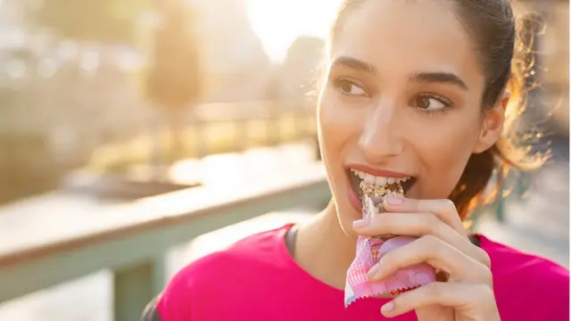 Mujer se alimenta con una barra de cereal