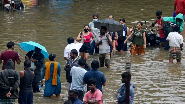 వర్షపు నీటిలో రోడ్లను దాటేందుకు ప్రయత్నిస్తున్న చెన్నైవాసులు