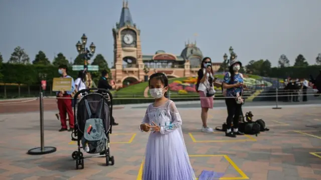 A girl wearing a face mask waits to enter the Disneyland amusement park in Shanghai on May 11, 2020