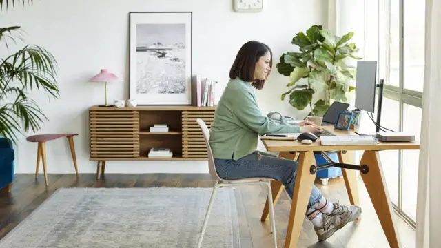 Imagen de una mujer trabajando desde la sala de una vivienda.