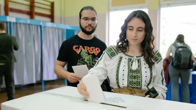 Bükreş'te bir sandıkta geleneksel beyaz kıyafetlerle oy kullanan bir kadın