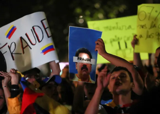 Un hombre sostiene un cartel junto a otros venezolanos que viven en México y miembros del Comando ConVzla durante una protesta contra los resultados electorales que otorgaron al presidente venezolano Nicolás Maduro un tercer mandato, frente al monumento del Ángel de la Independencia en la Ciudad de México, México, el 30 de julio de 2024. 