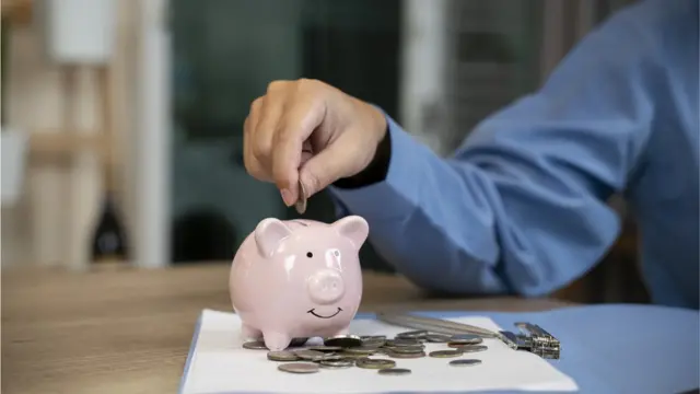 Une personne met de l'argent dans une tirelire